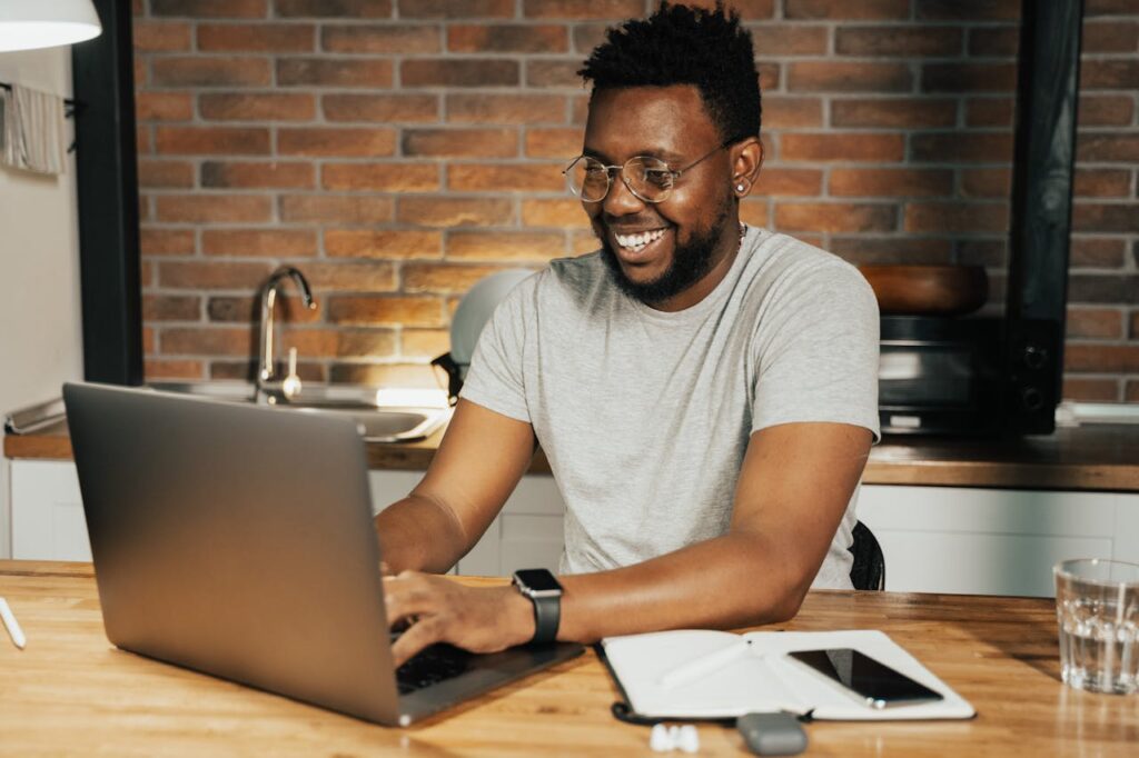 A man in glasses reads content on his laptop at home.