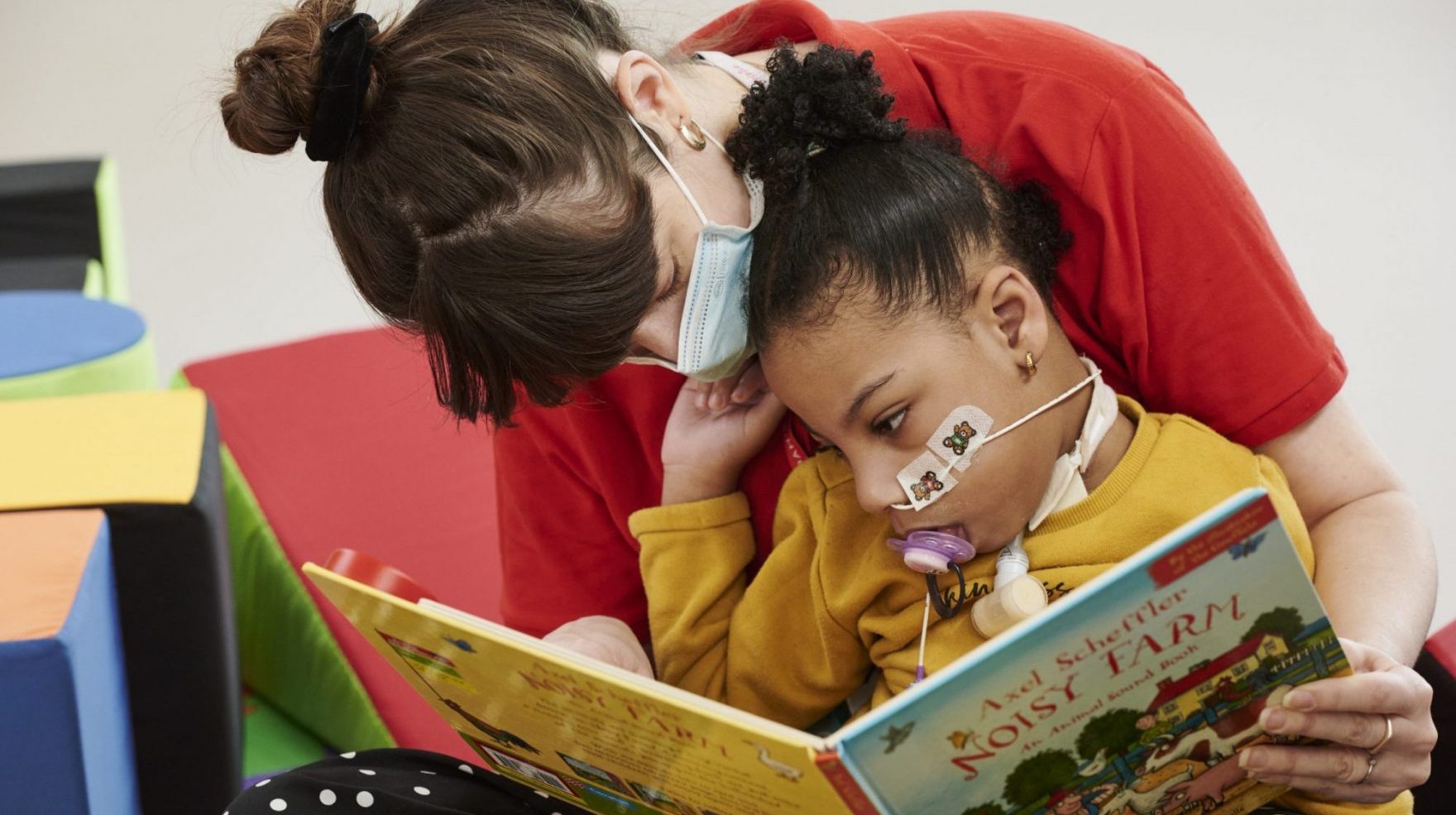 A Noah’s Ark Children’s Hospice volunteer reads a book to a young girl.