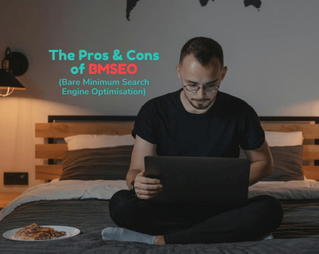 A man works on his laptop while sitting in bed beside a pizza.
